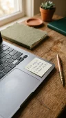 A small handwritten sticky note resting on the corner of a laptop beside a copper pen